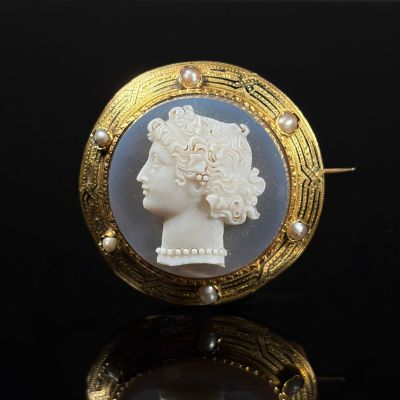 an image of a white and gold broocher with a woman ' s head