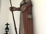 une statue représentant un homme tenant un bâton, placée dans un coin