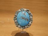 Bague en turquoise avec des touches d'argent, posée sur une table en bois