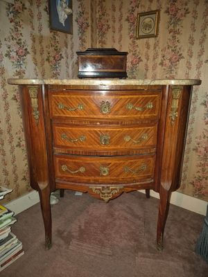 une commode avec un plateau en marbre dans un coin de la pièce