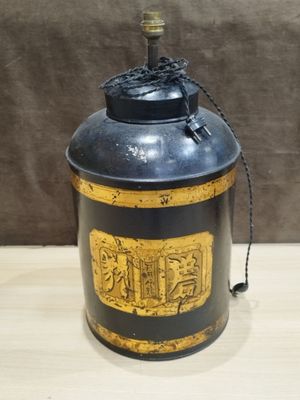 une vieille boîte noire et dorée posée sur une table en bois