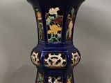 un vase bleu orné d'un motif, posé sur une table