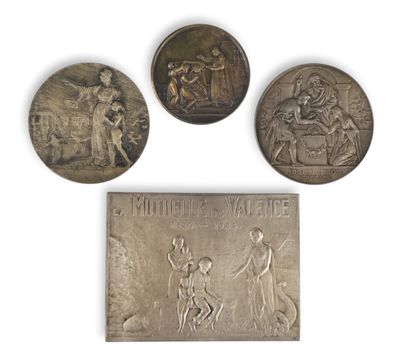 three silver medals of various sizes and shapes on a white surface