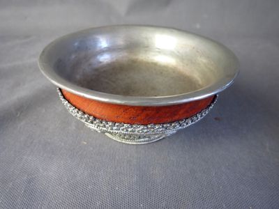 un bol en argent bordé de rouge posé sur une table