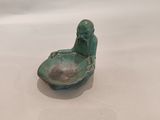 une petite figurine représentant un homme assis dans un bateau