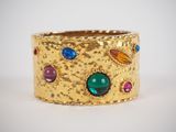 an image of a close up of a gold ring with multi colored stones