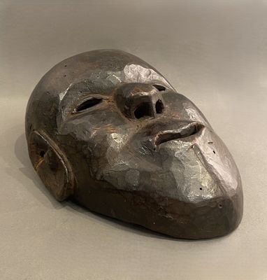 un masque métallique posé sur une table, sur fond blanc