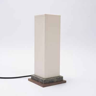 un gros plan d'une lampe posée sur une surface blanche, avec un cordon noir