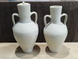 two white vases that are sitting on a table