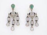 une photo d'une paire de boucles d'oreilles ornées de pierres vertes et blanches