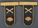two black and gold embroidered badges with crossed swords on them