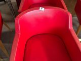 Plusieurs chaises rouges sont alignées en rang dans une pièce