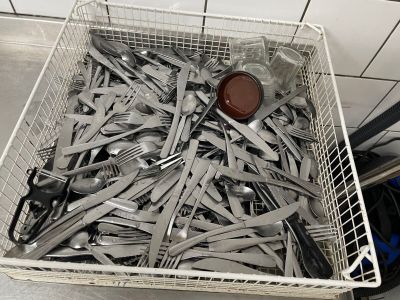 un panier rempli de fourchettes et de cuillères posé par terre