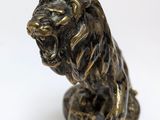statue of a lion sitting on a rock on a white background