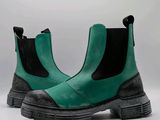 des bottes vertes avec des semelles noires et des bords noirs sur fond blanc