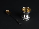 a silver cup and a spoon on a black table