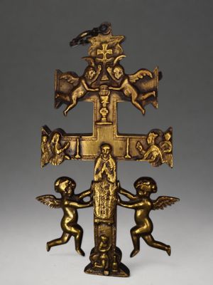 une image représentant une croix en or sur laquelle figurent des anges et un oiseau