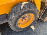 a large tire on the back of a yellow truck