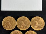 six souverains d'or dans une vitrine posée sur un socle noir