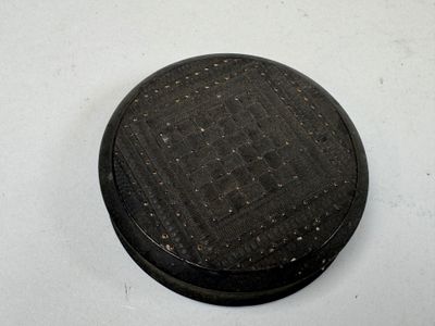 un petit objet noir posé sur une table avec un fond blanc