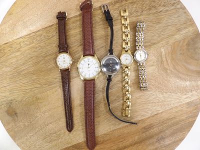 three watches and a bracelet are sitting on a wooden table