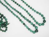 a close up of a strand of green beads on a white surface