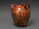 un vieux vase marron orné de motifs, posé sur une surface grise