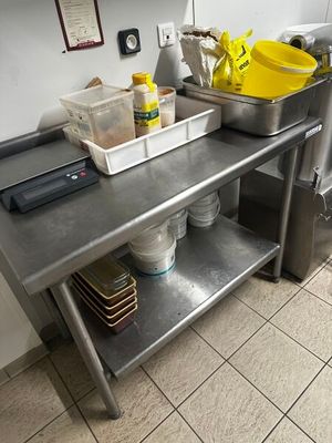 une cuisine avec une table en métal et une étagère en métal sur laquelle sont posés des plats