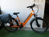 un vélo orange garé à côté d'une porte, avec un sac posé dessus