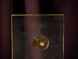 a gold coin in a glass box on a purple cloth