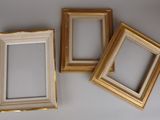 three gold picture frames sitting on top of a white table