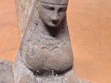 a stone statue of a woman sitting on a bench