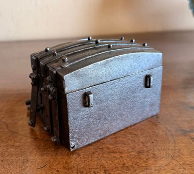 une petite boîte en métal posée sur une table, à côté d'un vase