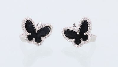 une paire de boucles d'oreilles en forme de papillons noirs et blancs sur un fond blanc