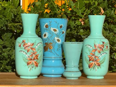 trois vases posés sur une table devant un buisson