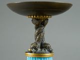 a blue glass vase with a gold base and a lion on it
