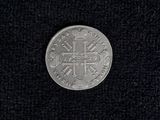 a silver coin with a cross on it on a black surface