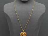 a gold necklace with a heart shaped pendant on a mannequin