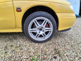 a yellow car that is parked in a gravel lot