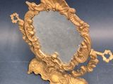 un miroir doré posé sur un pied, dans lequel se trouve une clé