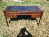 un bureau en bois avec un plateau en verre, posé dans l'herbe