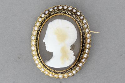 un gros plan sur le profil d'une femme portant une broche ornée de perles