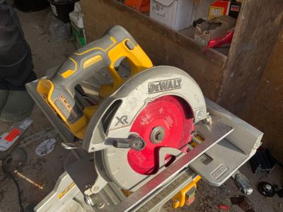 quelqu'un utilise une scie circulaire pour couper une pièce de bois