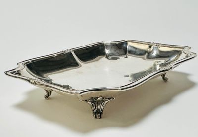 un plateau d'argent antique sur un support sur une surface blanche
