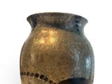 a black and gold vase sitting on a white surface