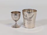a silver cup and a silver goblet sitting on a table