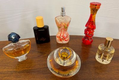 many different perfumes on a table with a white wall in the background