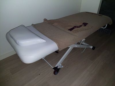 une table de massage recouverte d'une serviette, dans une pièce