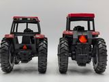 two toy tractors sitting next to each other on a white surface