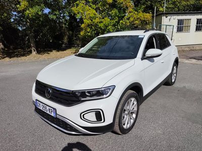 the white volkswagen suv is parked on the street in front of a house
